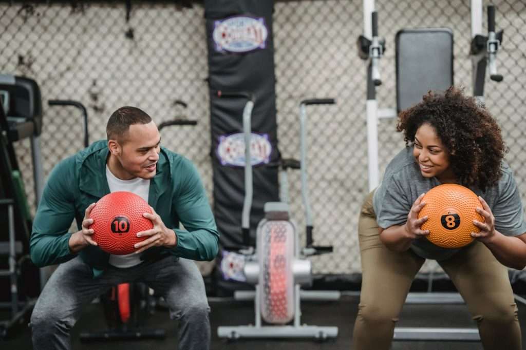 professional-trainer-and-black-woman-smiling-and-training-6455828 Diverse man and plump woman exercising with bright balls in sport club with gym equipment
